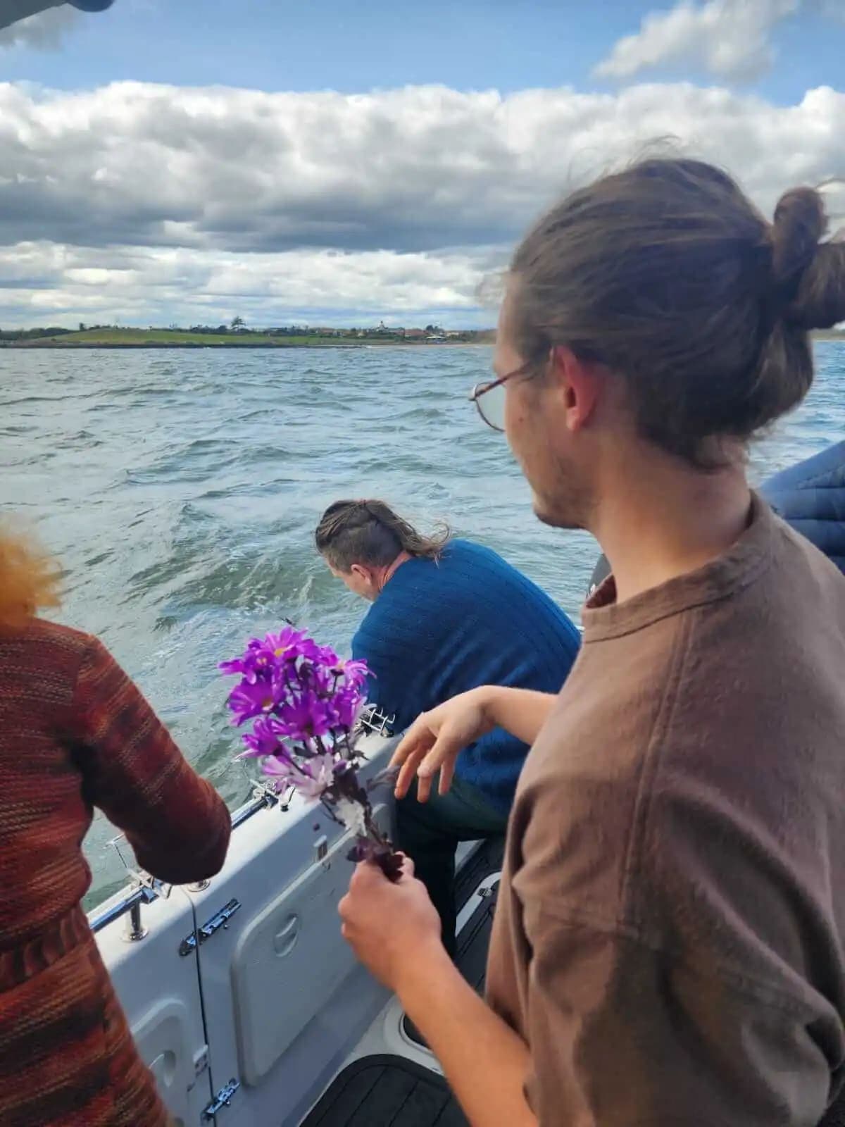 Family members with flowers at the side of the boat during a farewell