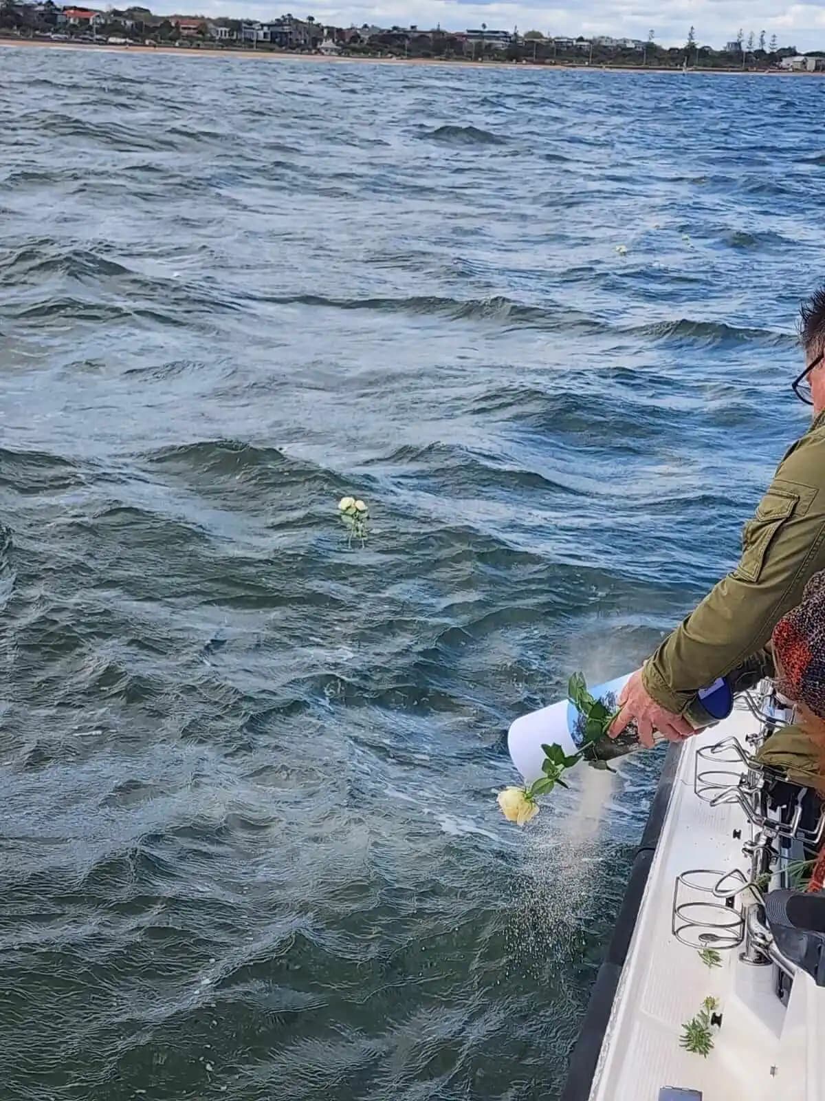 Flowers being placed on the water from the side of the boat