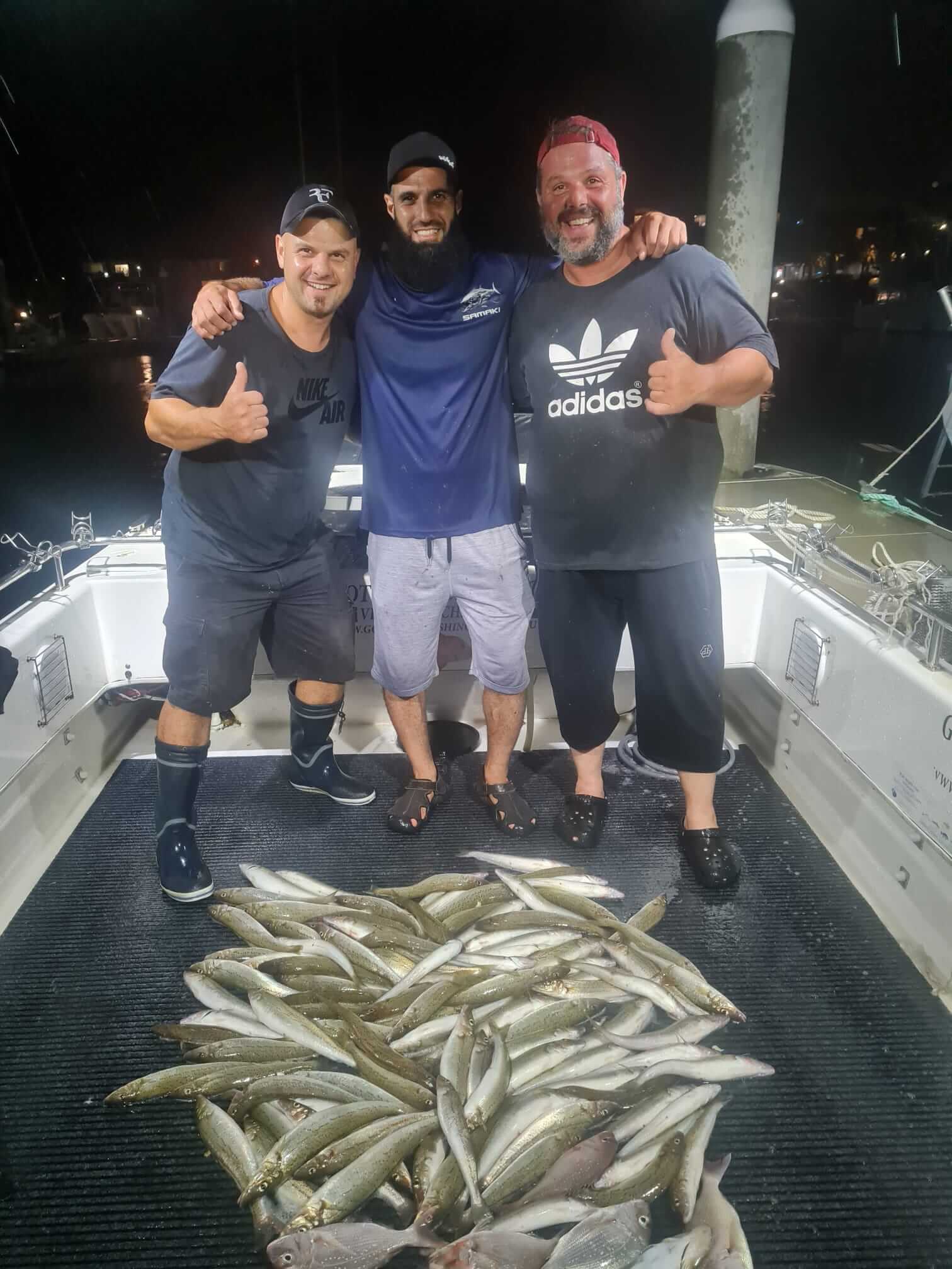 Three men with fishes and thumbs up